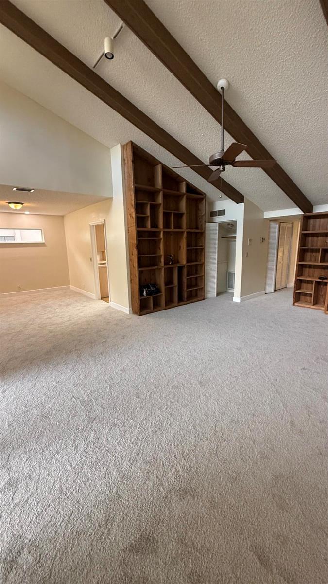 A living room with vaulted ceilings, exposed wooden beams, built-in shelving, and wall-to-wall carpeting — 6464 Pumpkin Seed Circle, Boca Raton FL 33433, BOCA RATON, FL
