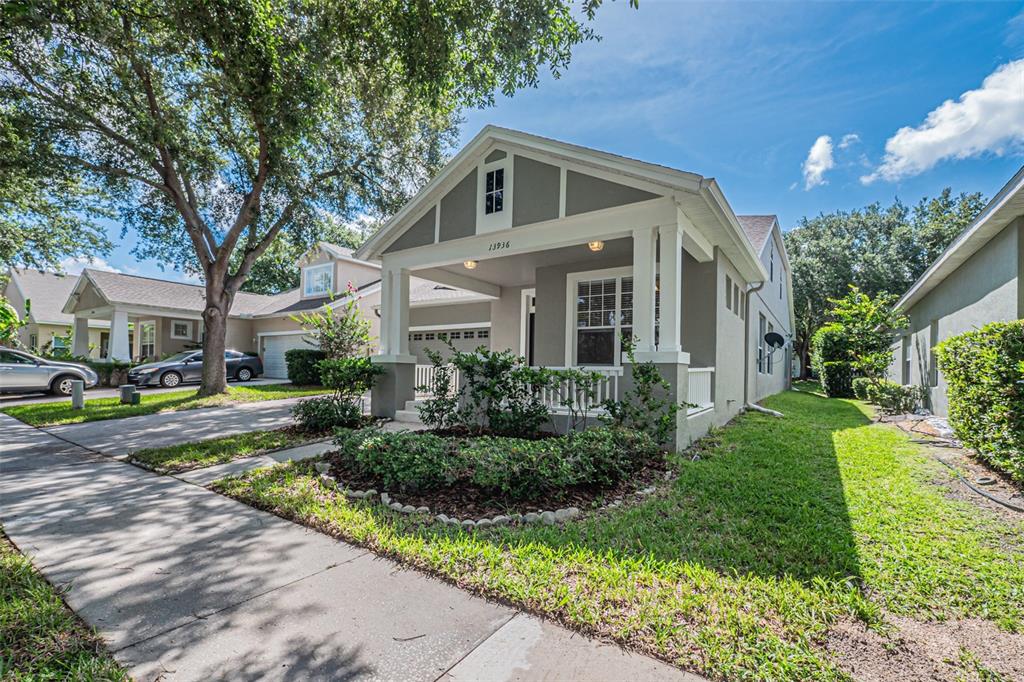 A single-story house with a covered front porch, gray siding, and a landscaped front yard — 13936 EDEN ISLE BOULEVARD, WINDERMERE, FL