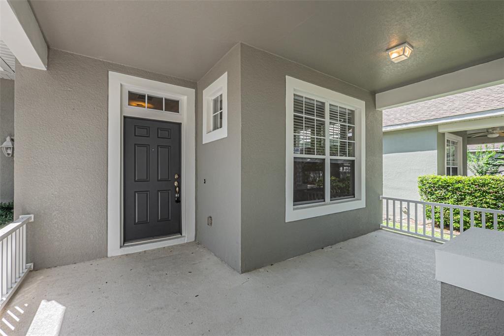 A covered front porch with a dark gray door, white trim, and a window — 13936 EDEN ISLE BOULEVARD, WINDERMERE, FL