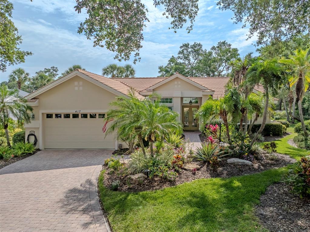 A single-story house with a beige exterior, a tiled roof, and a paved driveway — 417 WELLINGTON COURT, VENICE, FL