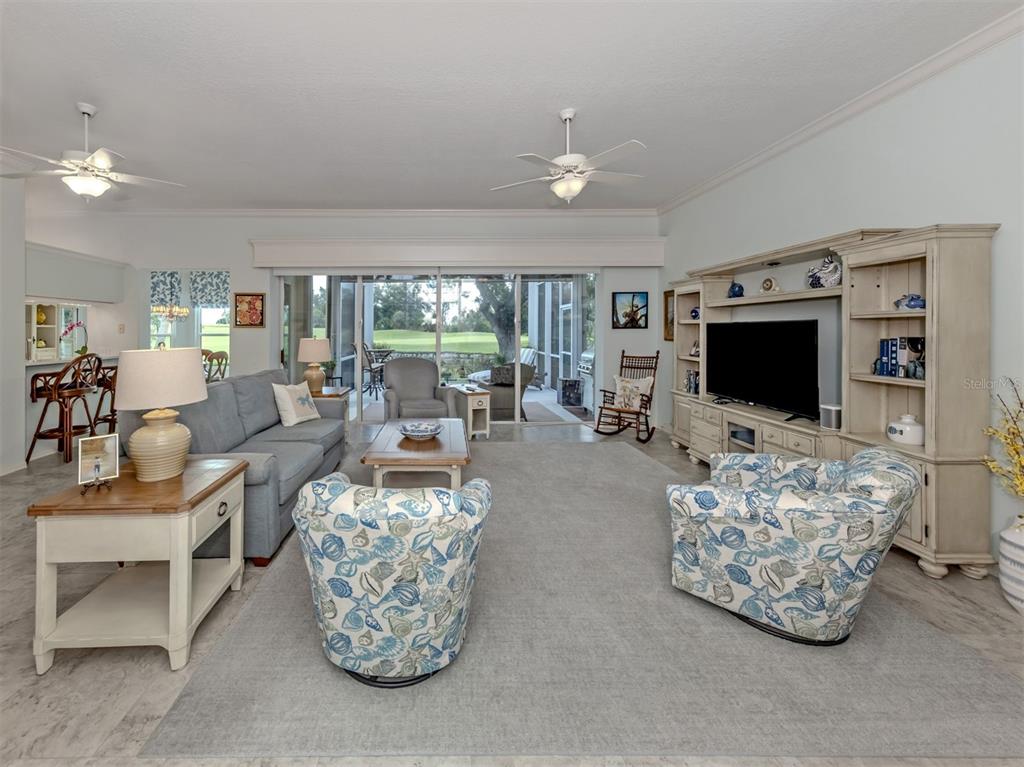 A living room features a large gray sofa, two patterned armchairs, and a media center — 417 WELLINGTON COURT, VENICE, FL