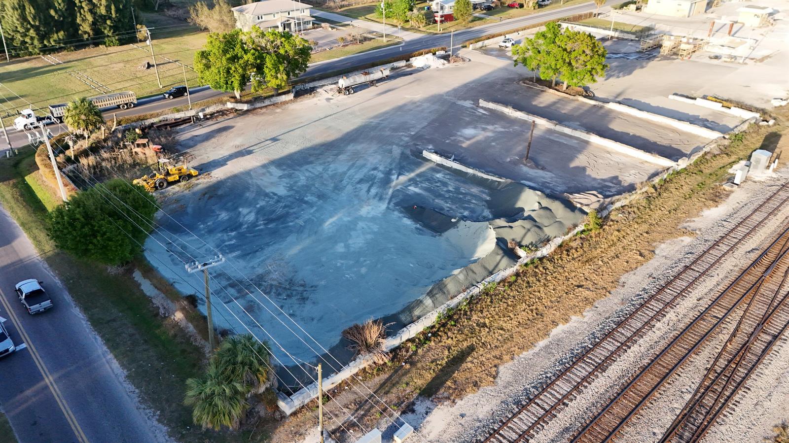 An aerial view shows a large, cleared dirt lot adjacent to railroad tracks and roads — 805 NW 9th Street, Okeechobee FL 34972, OKEECHOBEE, FL