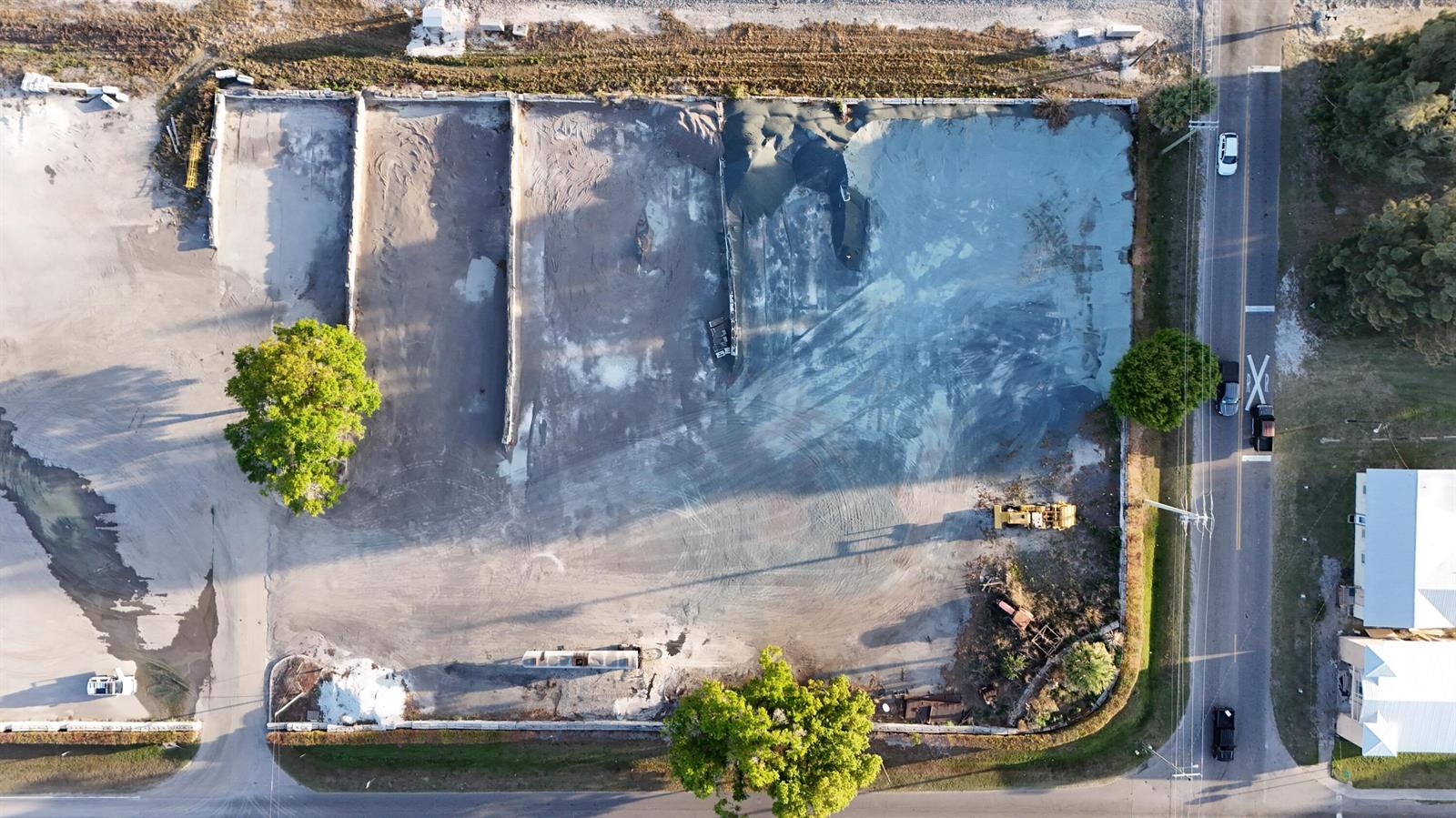An aerial view shows a large, cleared dirt lot with several trees and construction equipment — 805 NW 9th Street, Okeechobee FL 34972, OKEECHOBEE, FL