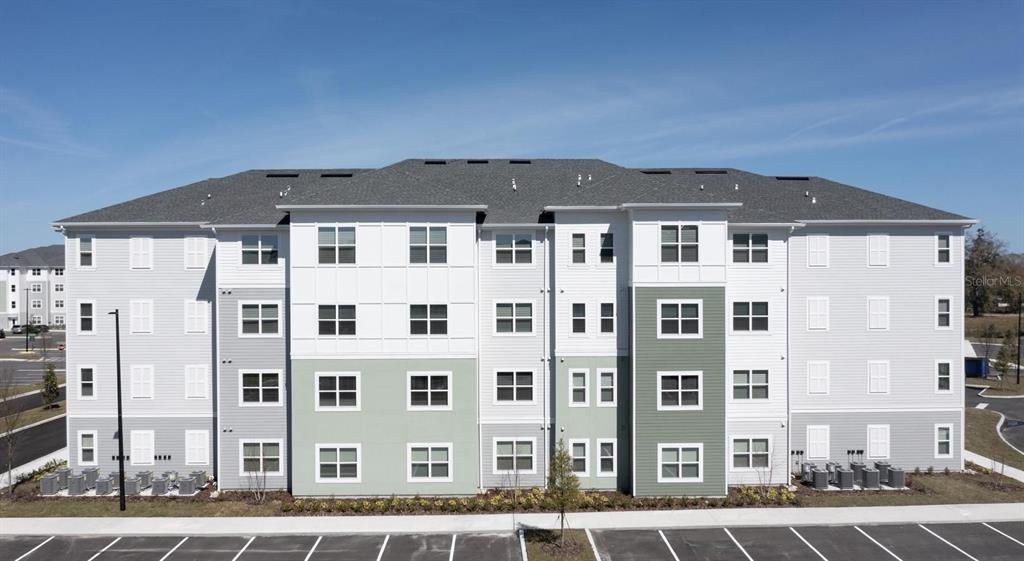 An exterior view of a four-story apartment building with gray and white siding — 110 ZORA PLACE UNIT B1, ORLANDO, FL