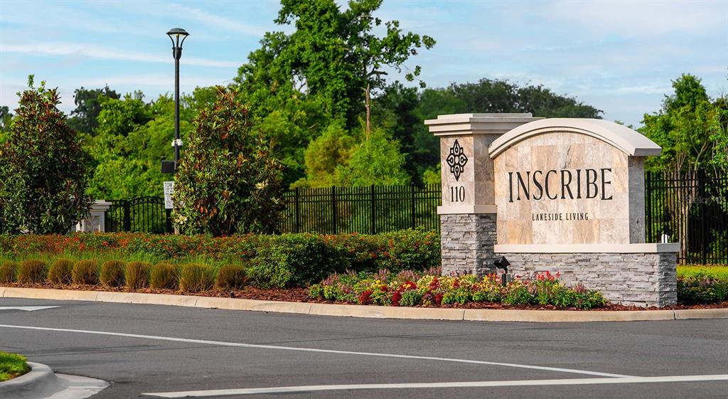 A stone monument sign for Inscribe Lakeside Living stands beside a road with landscaping — 110 ZORA PLACE UNIT B1, ORLANDO, FL
