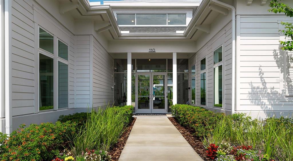 A concrete walkway leads to the glass-paned entrance of a white building with horizontal siding — 110 ZORA PLACE UNIT B1, ORLANDO, FL