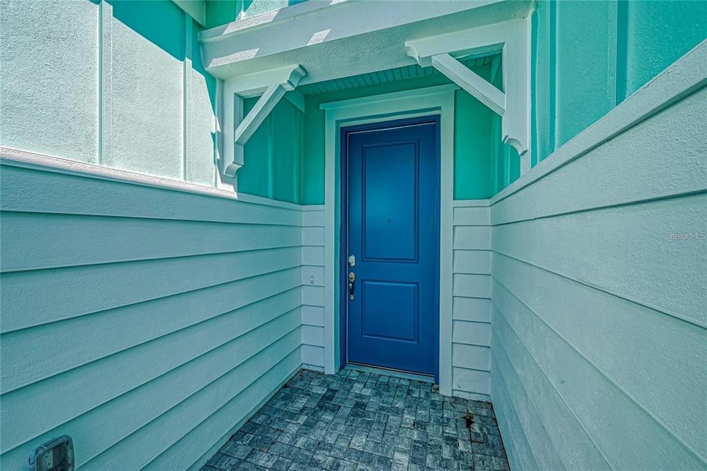 A bright blue front door is set within a light teal exterior entryway with pavers — 306 HANG LOOSE WAY, DAYTONA BEACH, FL