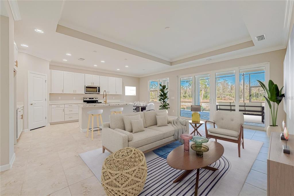 An open-concept living room and kitchen featuring white cabinetry, tile flooring, and large glass doors — 306 HANG LOOSE WAY, DAYTONA BEACH, FL