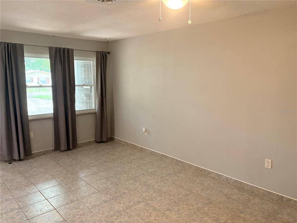 A room with gray walls, tiled flooring, and windows covered by dark gray curtains — 6010 TENNESSEE AVENUE, NEW PORT RICHEY, FL
