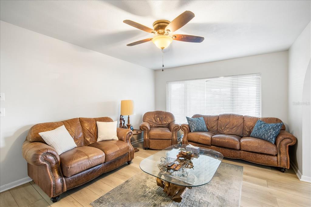 A living room features brown leather furniture, a glass coffee table, and light wood flooring — 1016 LADY GUINEVERE DRIVE, VALRICO, FL