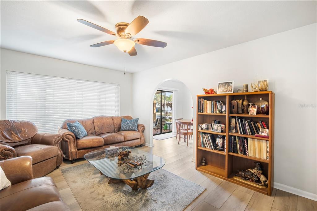 A living room with leather furniture, a glass coffee table, and a wooden bookshelf — 1016 LADY GUINEVERE DRIVE, VALRICO, FL