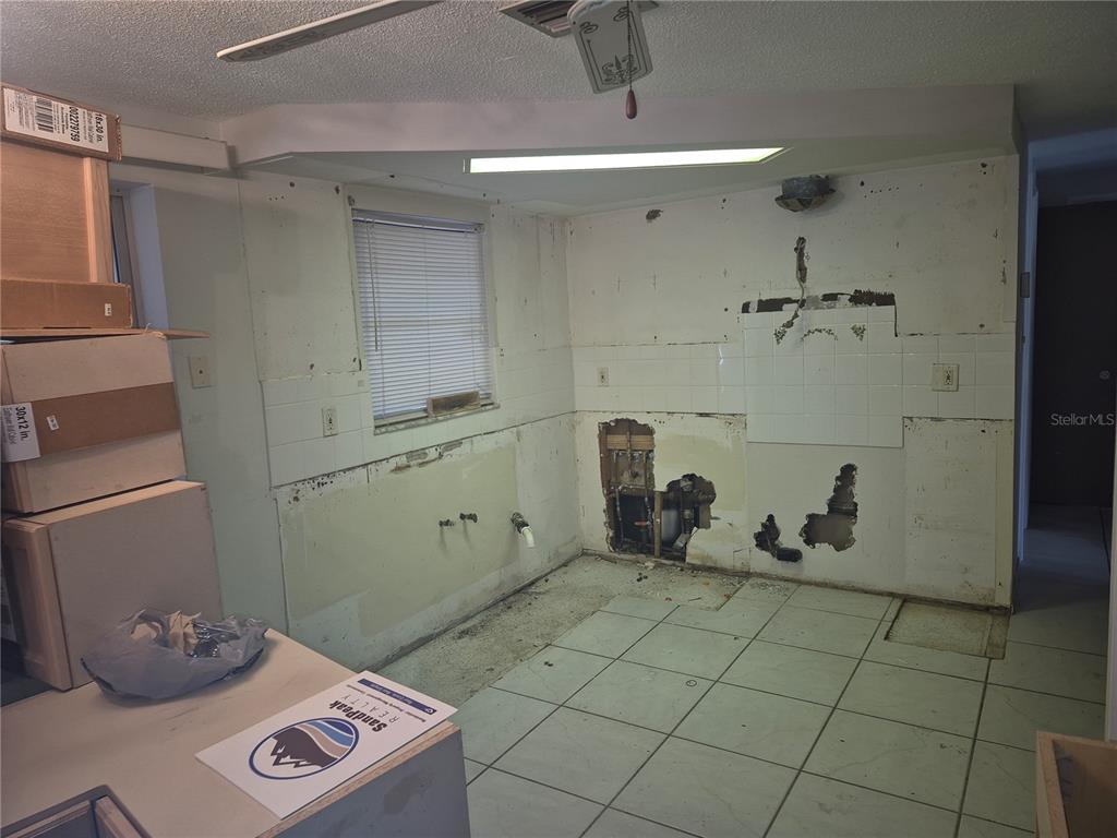 A kitchen under renovation with exposed wall studs, plumbing, and stacked cardboard boxes — 3245 FAIRMOUNT DRIVE, HOLIDAY, FL
