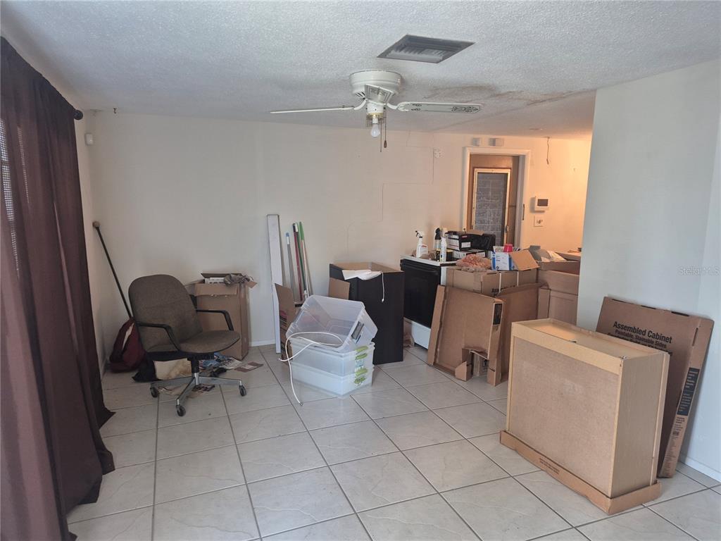 A room with tile flooring, a ceiling fan, and several cardboard boxes and furniture pieces — 3245 FAIRMOUNT DRIVE, HOLIDAY, FL