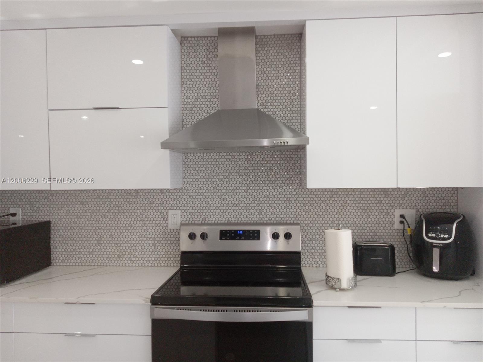 A modern kitchen features white cabinets, a stainless steel range hood, and a penny-tile backsplash — 8224 NW 9th Ct # 3, Plantation FL 33324, PLANTATION, FL