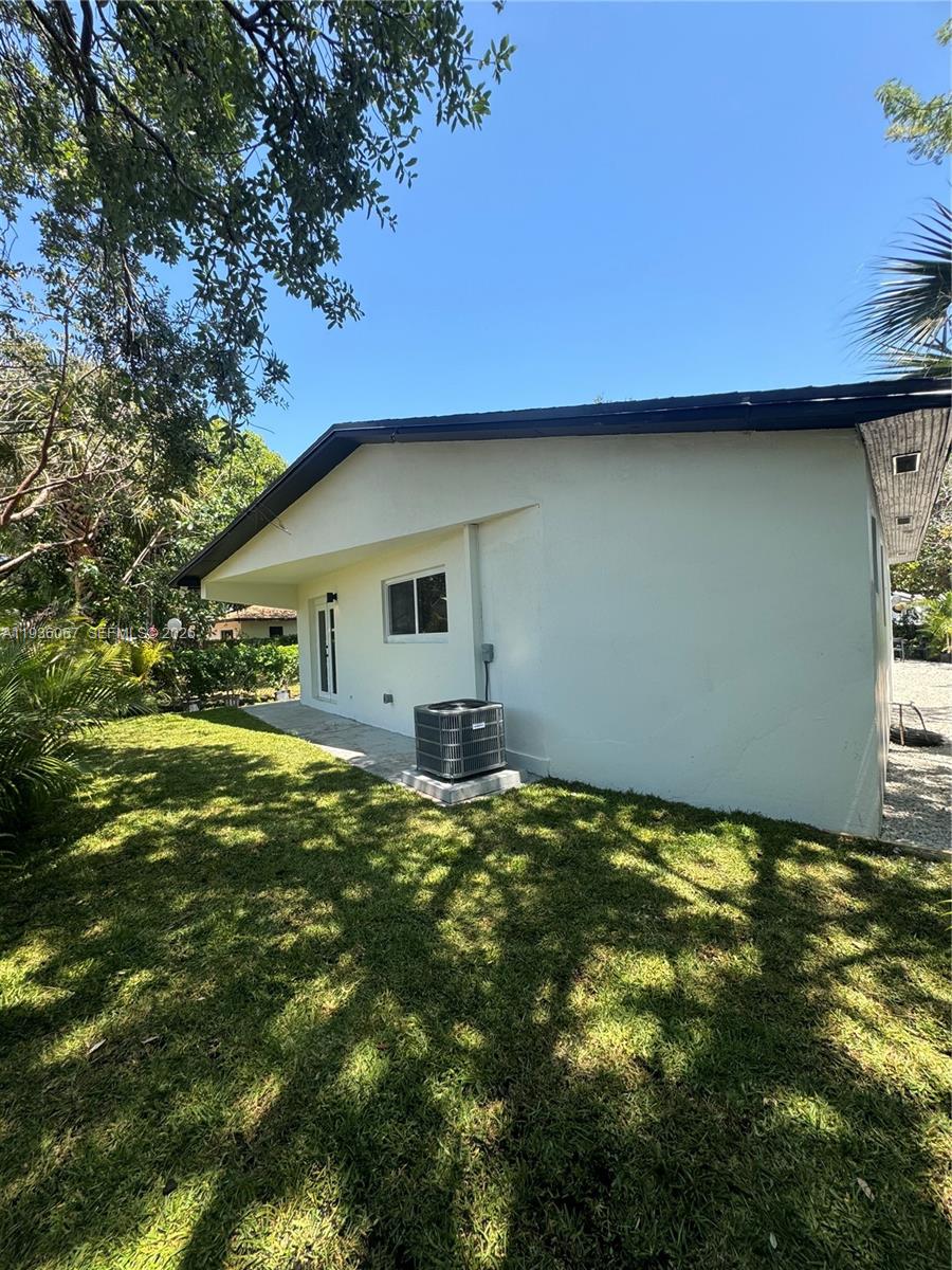 The exterior of a white house features a lawn, an air conditioning unit, and trees — 111 NW 7th Ave, Dania Beach FL 33004, DANIA BEACH, FL