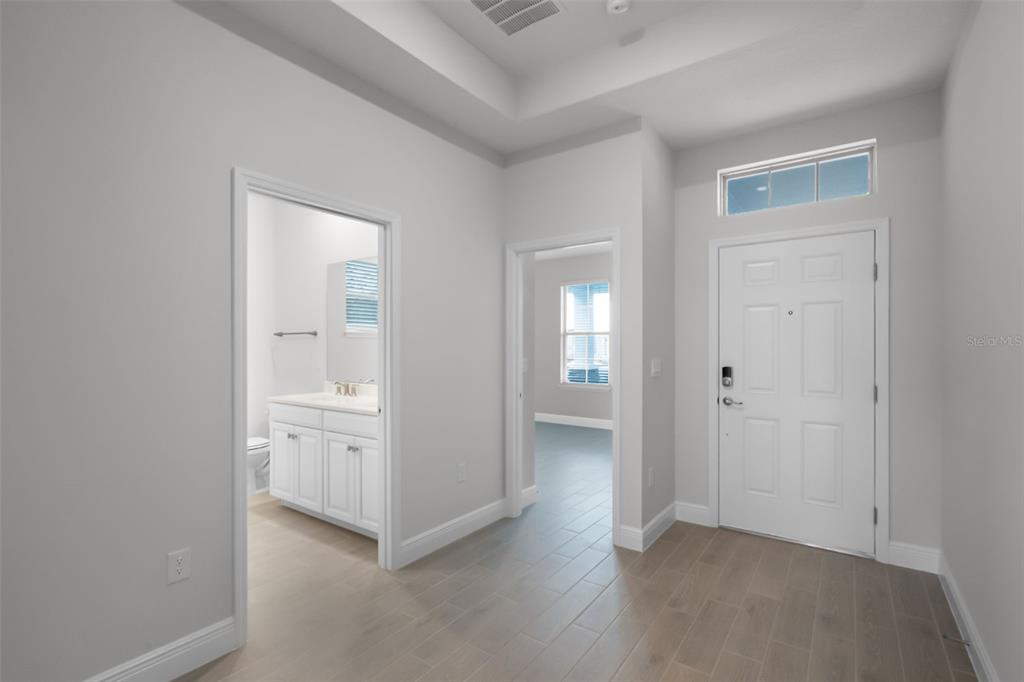 An entryway with light wood-look tile flooring, a white front door, and two interior doorways — 11899 SHINE VIEW LANE, WINTER GARDEN, FL