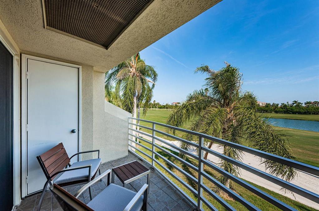 A balcony with two chairs and a table overlooks a golf course and a pond — 6151 BAHIA DEL MAR BOULEVARD UNIT 226, ST PETERSBURG, FL