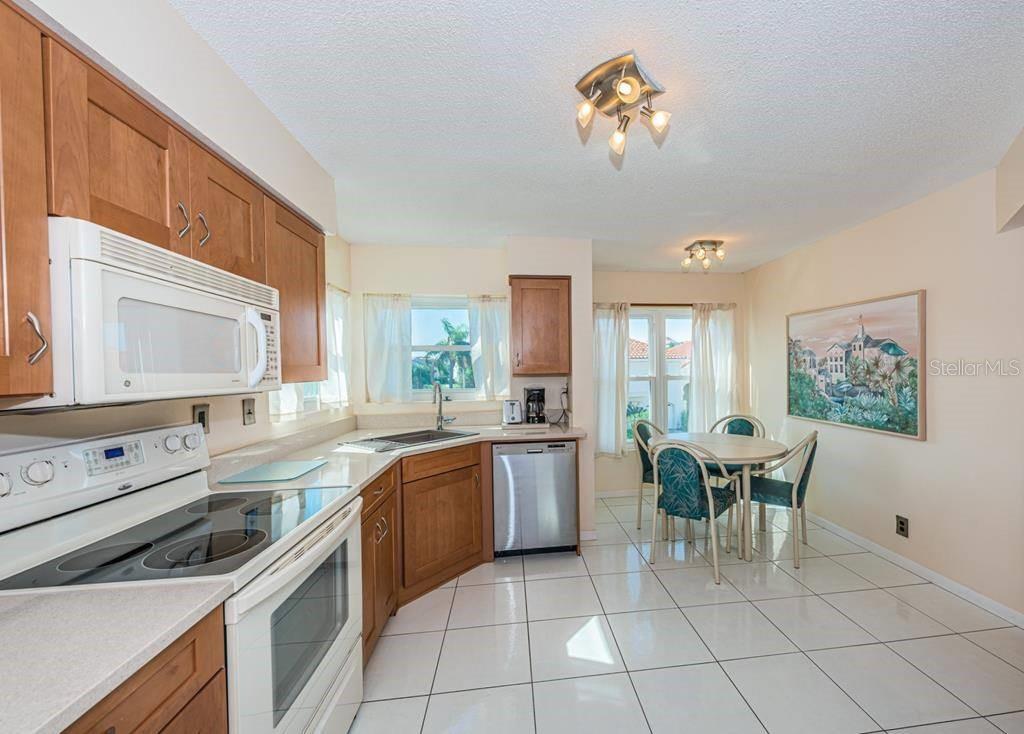 A kitchen with wood cabinets, white appliances, and a dining area with a table — 6151 BAHIA DEL MAR BOULEVARD UNIT 226, ST PETERSBURG, FL