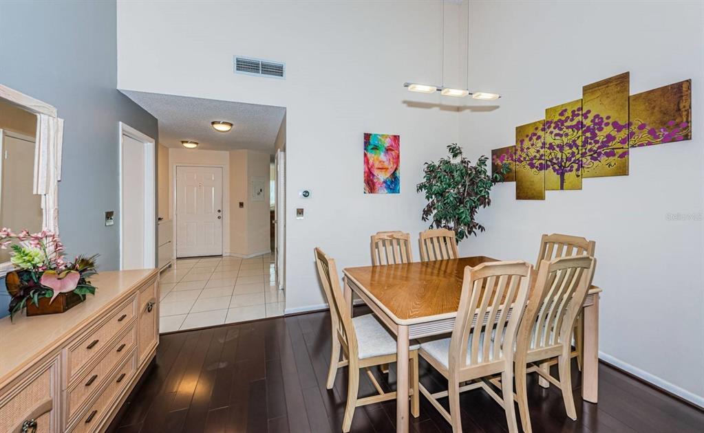 A dining room with a wooden table, six chairs, and wall art on dark flooring — 6151 BAHIA DEL MAR BOULEVARD UNIT 226, ST PETERSBURG, FL