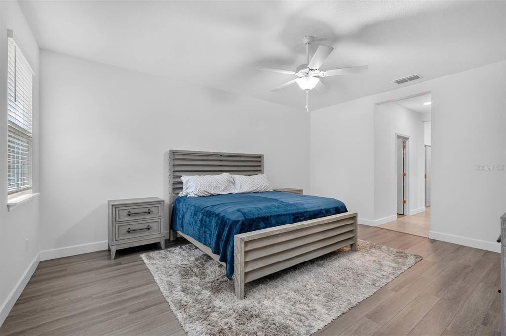 A bedroom features a wooden bed frame, a blue blanket, and a gray area rug — 23 BUD FIELD DRIVE, PALM COAST, FL