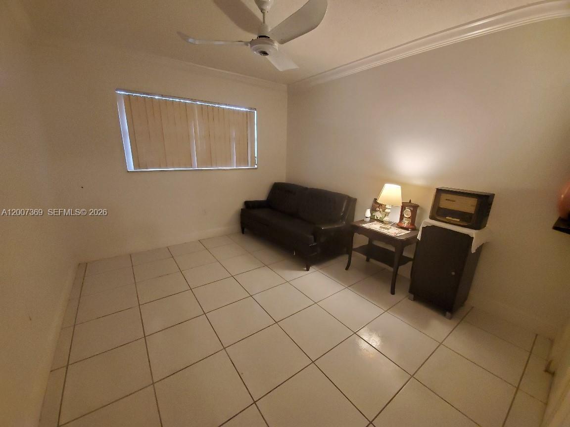 A room with white tile flooring, a dark sofa, and a ceiling fan — 1750 NE 191st St # 1, Miami FL 33179, MIAMI, FL