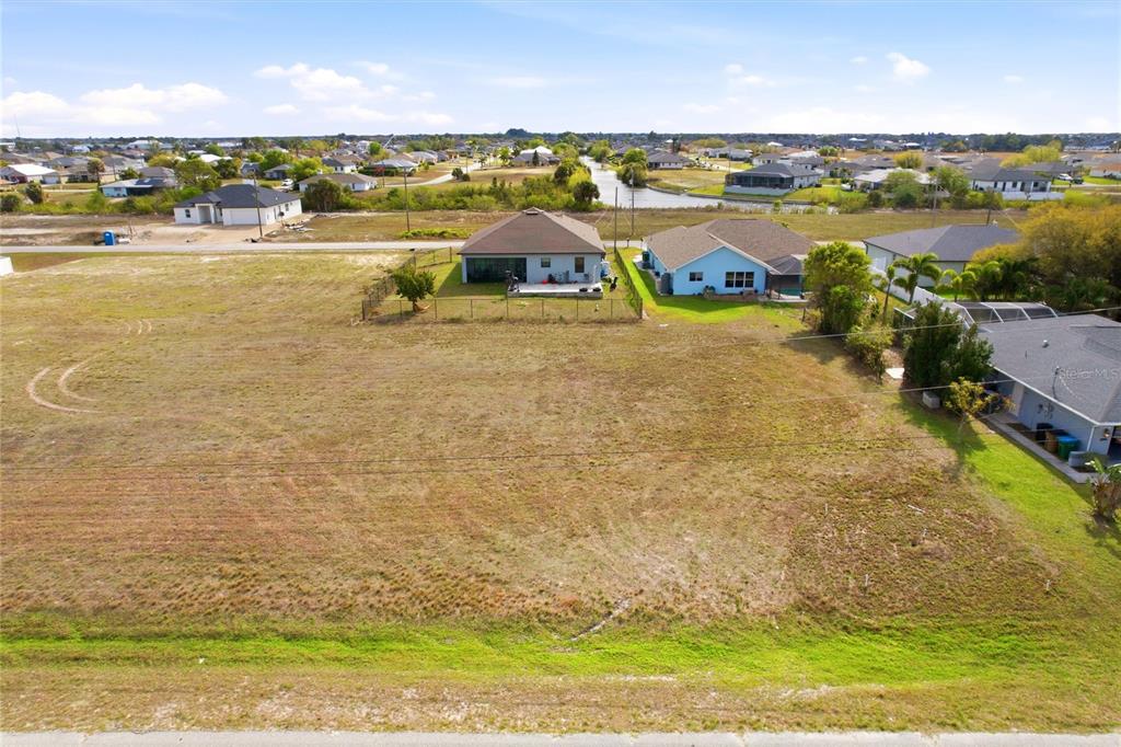 An aerial view shows a large, vacant residential lot situated between existing suburban houses — 217 NW 20TH AVENUE, CAPE CORAL, FL