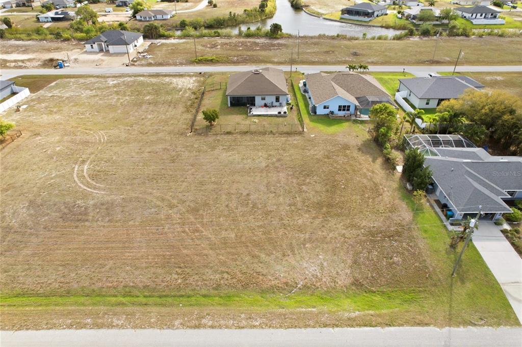 An aerial view shows a large, vacant residential lot situated between several existing houses — 217 NW 20TH AVENUE, CAPE CORAL, FL