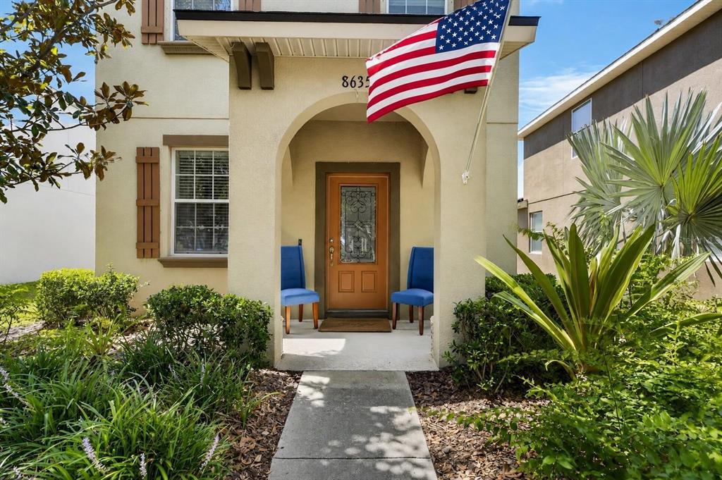 The exterior of a house features an arched entryway, a front door, and two chairs — 8635 TURNSTONE SHORE LANE, RIVERVIEW, FL