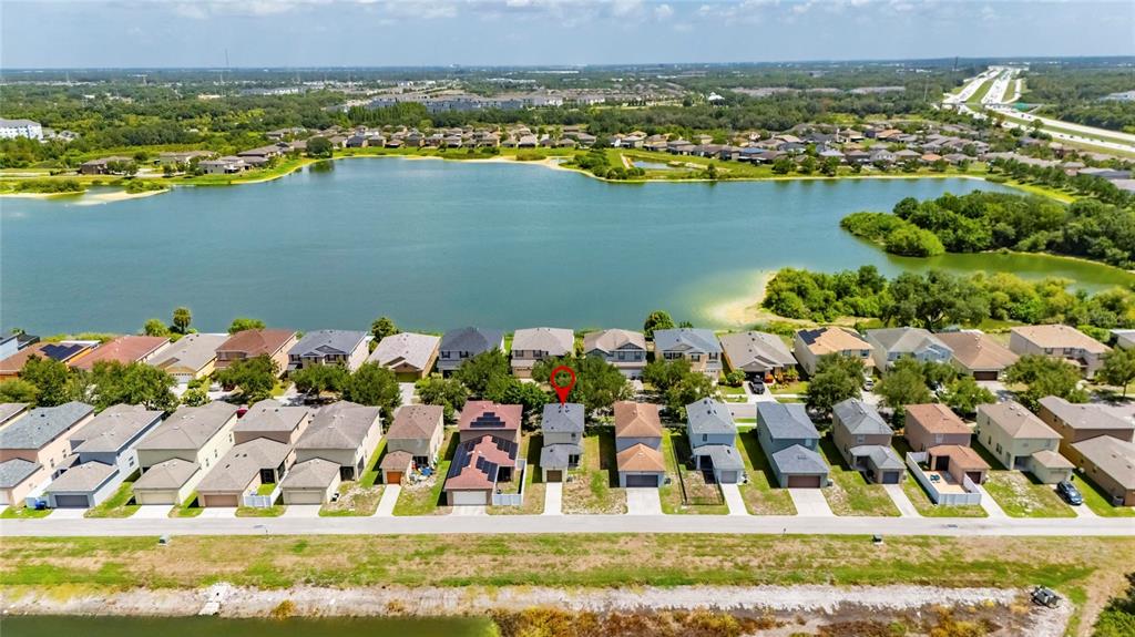 An aerial view shows a suburban neighborhood with houses bordering a large lake — 8635 TURNSTONE SHORE LANE, RIVERVIEW, FL