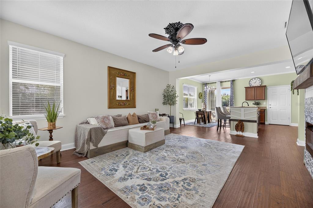 A living room with hardwood floors, a ceiling fan, and an open-concept dining area — 8635 TURNSTONE SHORE LANE, RIVERVIEW, FL