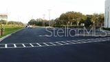 A paved parking lot with marked spaces sits in front of trees and a building — 3180 CURLEW ROAD UNIT 107, OLDSMAR, FL