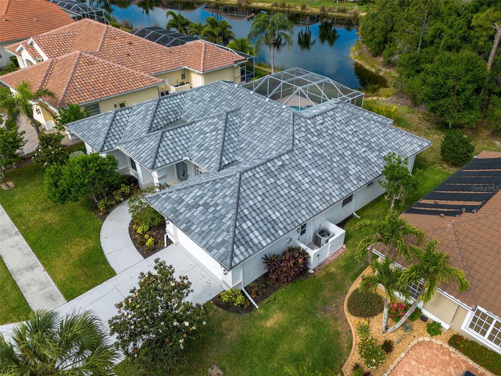 An aerial view shows a single-story house with a gray tiled roof and pool enclosure — 629 SAWGRASS BRIDGE ROAD, VENICE, FL