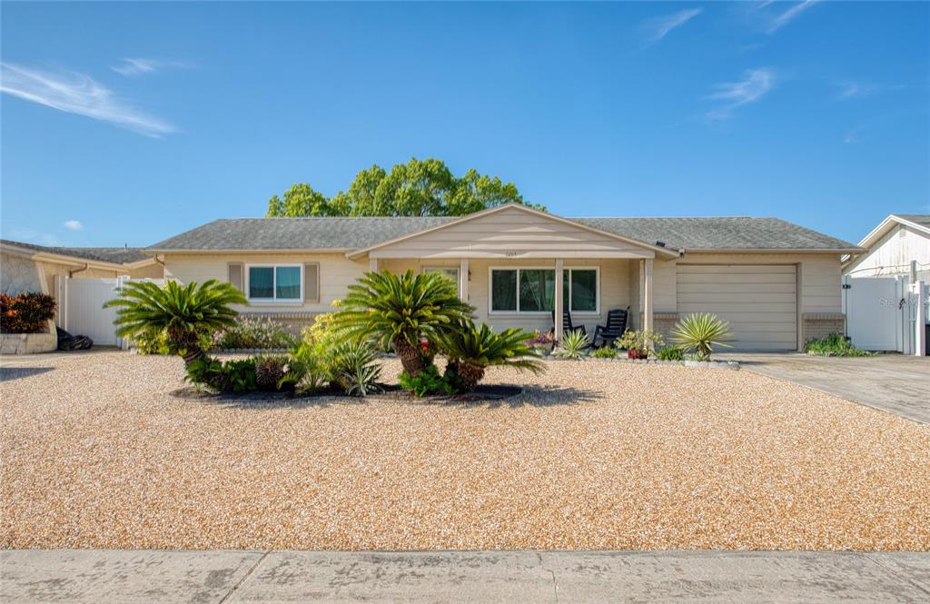 A single-story house with a gravel front yard, palm trees, and an attached garage — 6014 3RD AVENUE, NEW PORT RICHEY, FL