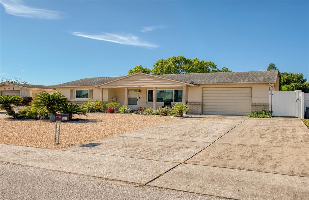 A single-story house with a beige exterior, gravel front yard, and an attached garage — 6014 3RD AVENUE, NEW PORT RICHEY, FL
