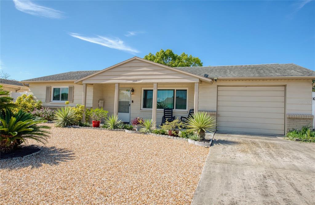 A single-story house with a beige exterior, a gravel front yard, and an attached garage — 6014 3RD AVENUE, NEW PORT RICHEY, FL