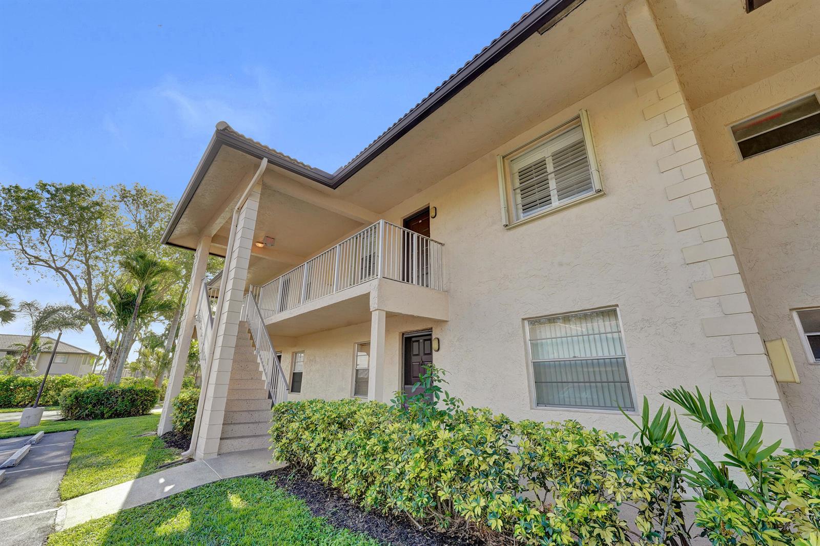 A two-story apartment building features a beige stucco exterior, a balcony, and an outdoor staircase — 5531 Lakeside Drive # 202, Margate FL 33063, MARGATE, FL