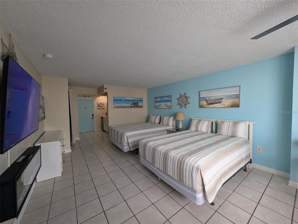 A bedroom features two beds, tiled floors, a wall-mounted television, and light blue accent walls — 313 S ATLANTIC AVENUE UNIT 3100, DAYTONA BEACH, FL