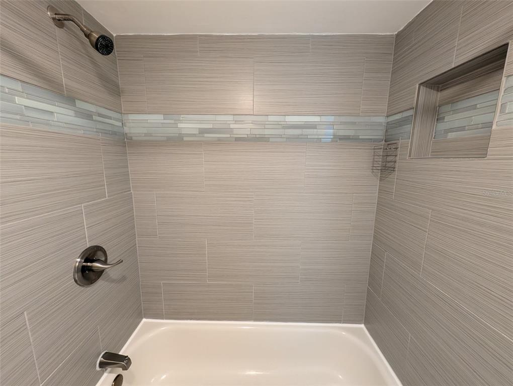 A tiled shower and bathtub combination features a horizontal glass accent tile border and niche — 313 S ATLANTIC AVENUE UNIT 3100, DAYTONA BEACH, FL