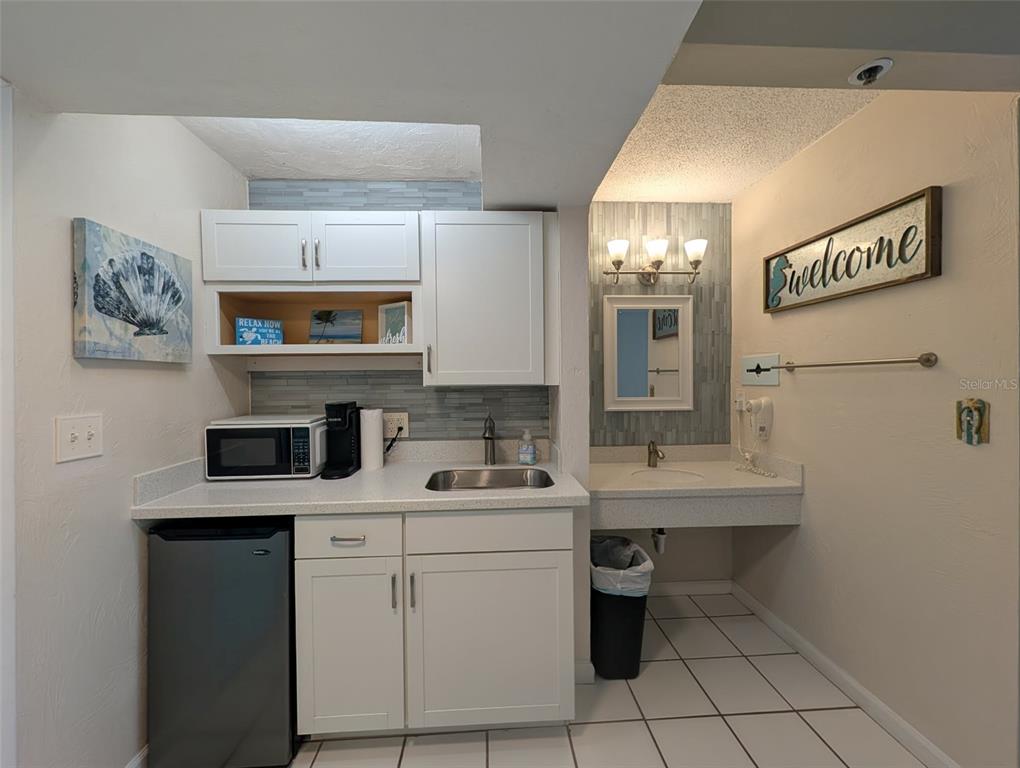 A kitchenette area features white cabinets, a small refrigerator, a sink, and a separate vanity — 313 S ATLANTIC AVENUE UNIT 3100, DAYTONA BEACH, FL