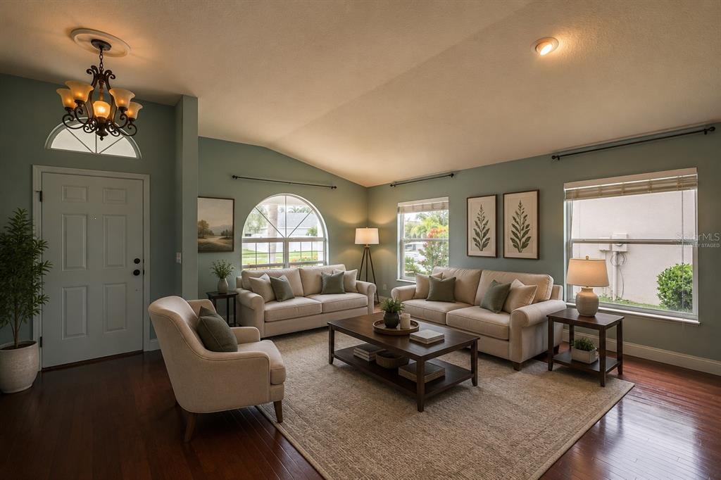 A living room with light blue walls, beige furniture, a wooden coffee table, and hardwood floors — 1761 BONITA BLUFF COURT, RUSKIN, FL
