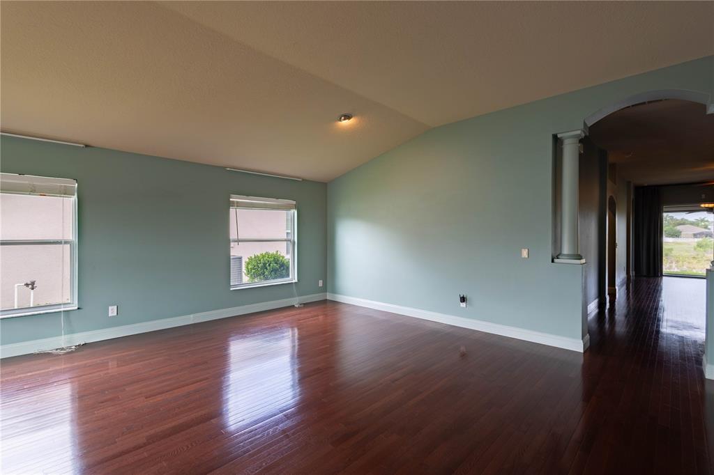 An empty room with dark hardwood floors, light blue walls, and a vaulted ceiling — 1761 BONITA BLUFF COURT, RUSKIN, FL