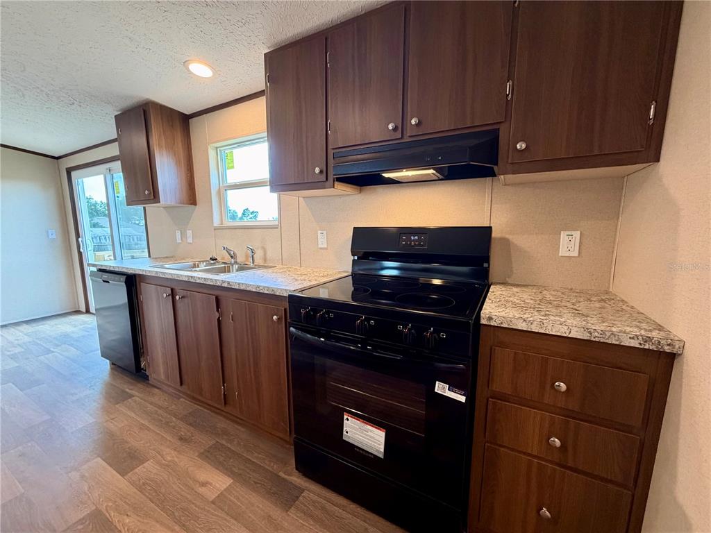 A kitchen features dark wood cabinets, black appliances, and a light-colored laminate countertop — 4507 BIG TANK ROAD, LAKE WALES, FL
