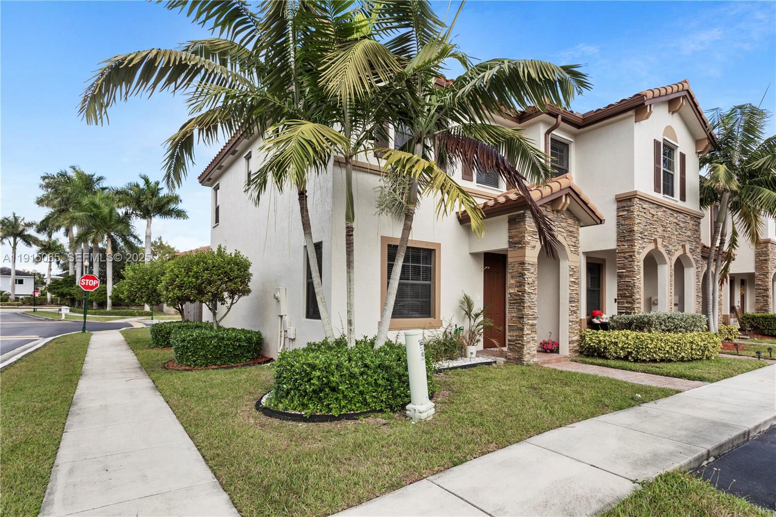 A two-story stucco townhouse with stone accents, palm trees, and a sidewalk in front — 3209 SE 4th Ct, Homestead FL 33033, HOMESTEAD, FL
