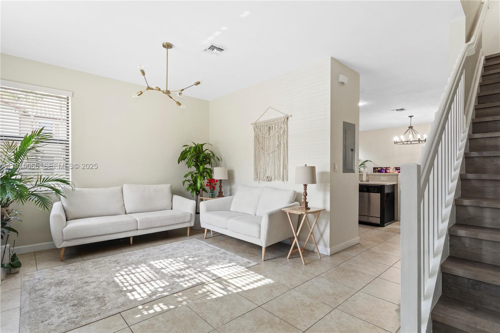 A living room features two white sofas, a rug, a chandelier, and a staircase — 3209 SE 4th Ct, Homestead FL 33033, HOMESTEAD, FL
