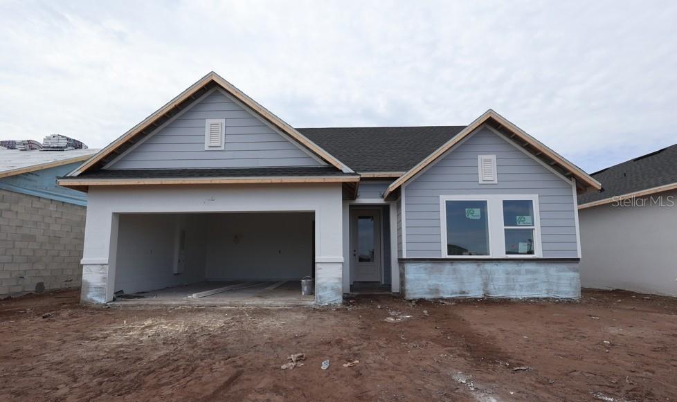 A newly constructed single-story house with a two-car garage and light blue siding — 5033 ORINOCO LANE, ST CLOUD, FL