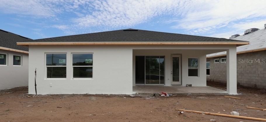 The rear exterior of a newly constructed house features a covered patio and stucco walls — 5033 ORINOCO LANE, ST CLOUD, FL