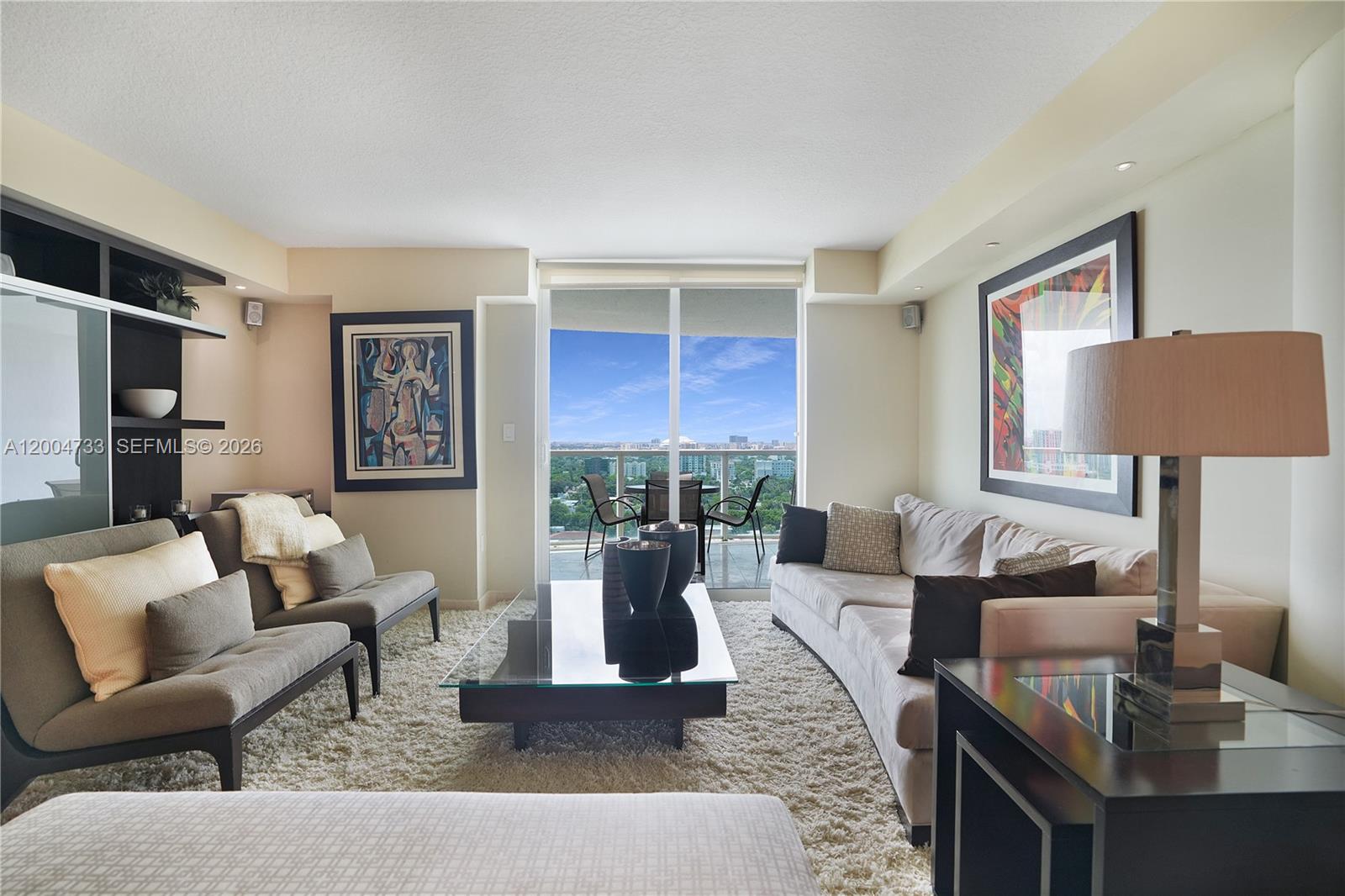 A living room features a glass coffee table, two sofas, and a balcony with city views — 2101 Brickell Ave # 1812, Miami FL 33129, MIAMI, FL