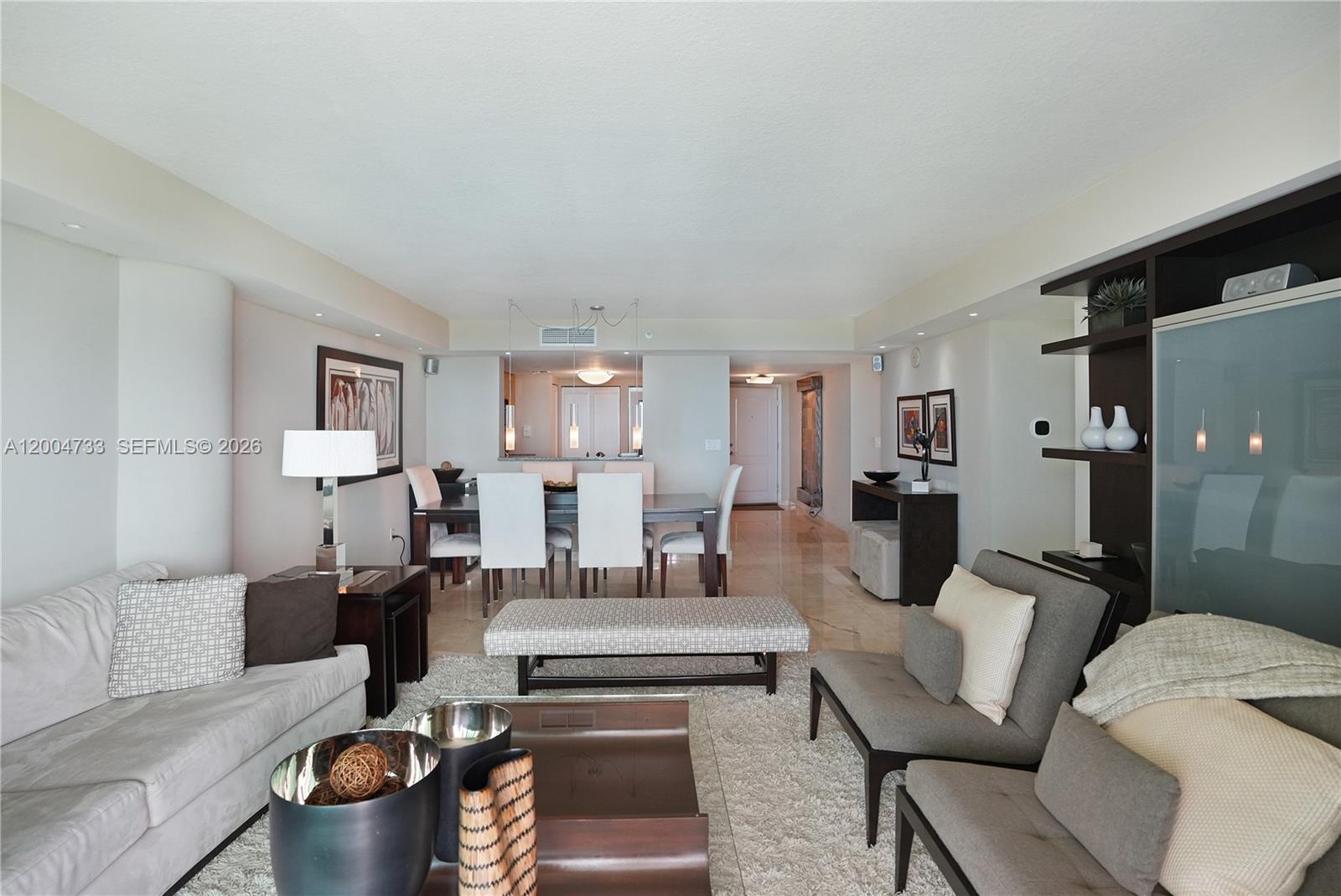 A living room and dining area feature neutral furniture, tile flooring, and modern lighting fixtures — 2101 Brickell Ave # 1812, Miami FL 33129, MIAMI, FL
