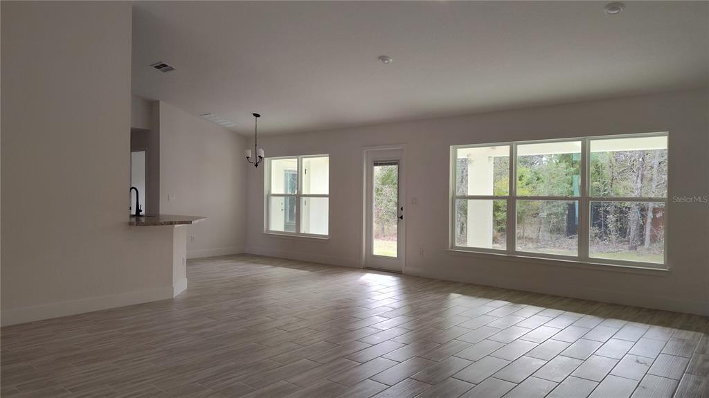 An open-concept living area features light-colored tile flooring, white walls, and large windows — 14159 GOLDFINCH ROAD, BROOKSVILLE, FL