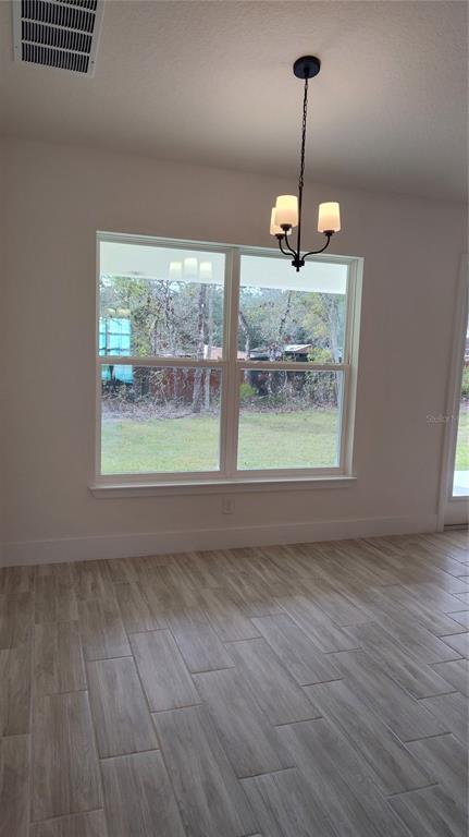 A dining area features light wood-look tile flooring, a black chandelier, and a large window — 14159 GOLDFINCH ROAD, BROOKSVILLE, FL